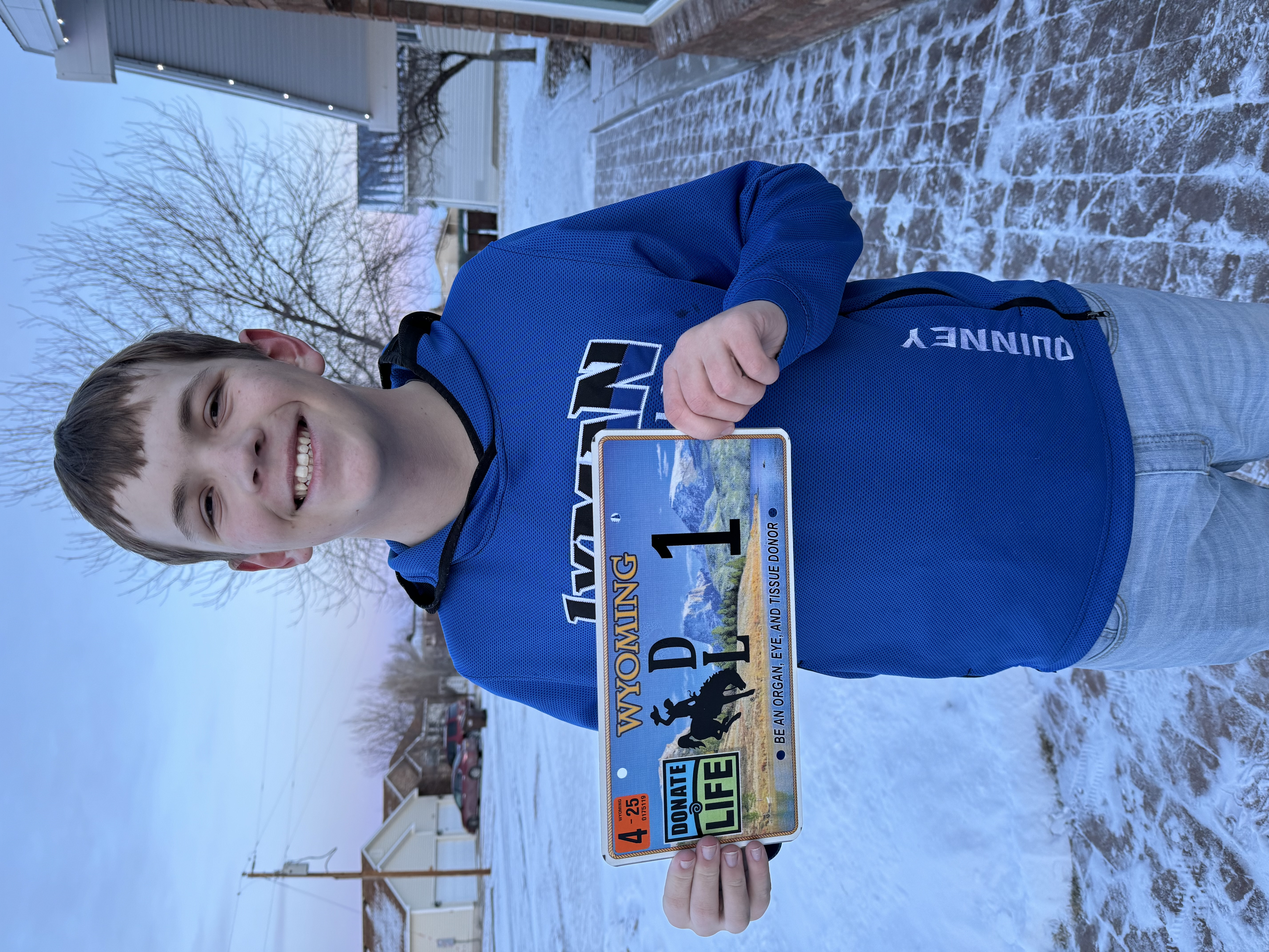 Bryson Quinney heart transplant recipient holding Donate Life Wyoming license plate number 1