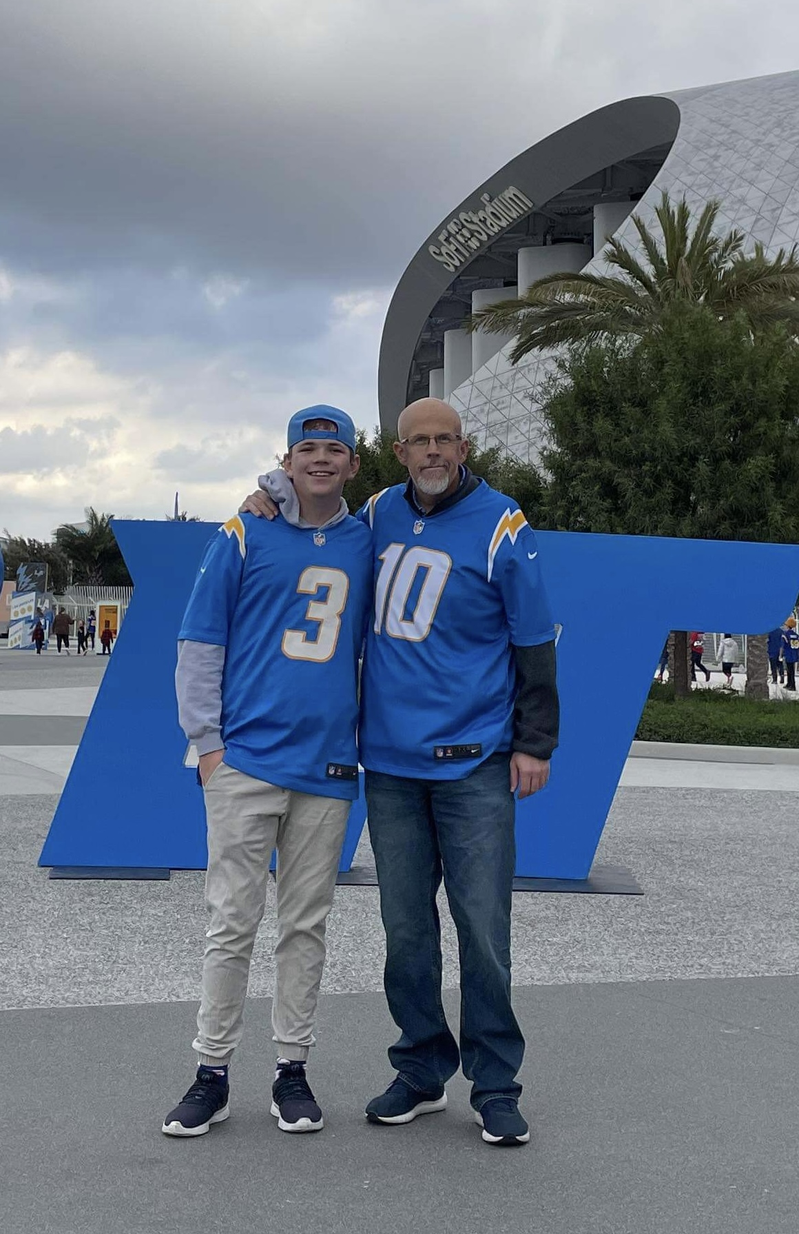 eric and bryson quinney, heart recipient from wyoming, in san diego chargers jerseys standing in front of san diego chargers stadium in california