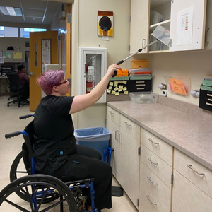 Alex shows off their grabber tool next to their desk.