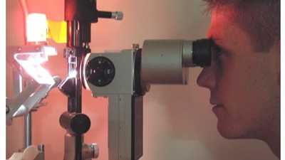eye technician looking at donated cornea through a slit lamp
