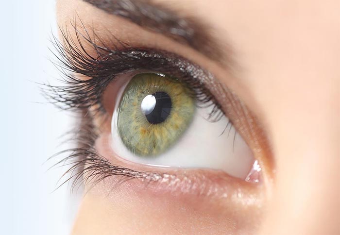 Close-up photo of a white woman's green eye looking upwards.